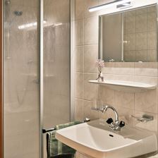 Bad mit Dusche, Waschbecken und Spiegel