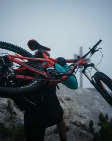 Kitzbüheler Alpen Hero Bike Ben Kalra trägt sein Mountainbike auf den Gipfel im PillerseeTal c Daniel Gollner
