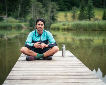 Kitzbüheler Alpen Hero Bike Ben Kalra zit op een steiger aan de Lauchsee in Fieberbrunn c Daniel Gollner