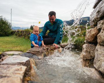 Kitzbühel Alps Hero O´Brien family Son is playing with his dad at the fountain in the Kneipp facility in Aschau c Daniel Gollner