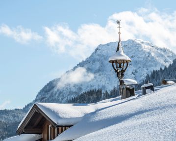 PillerseeTal: verschneites Bauernhaus mit Glockenstuhl