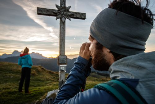 Vrouw bij de kruis op de top van de Baumooskogel - regio St. Johann in Tirol