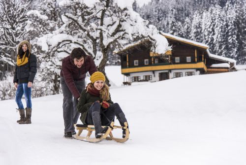 Tobogganer in front of a farm - St. Johann in Tirol region