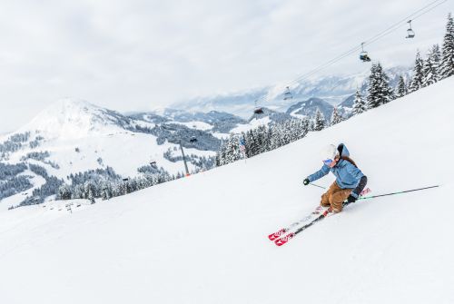 Skifahrerin auf Piste neben Sessellift