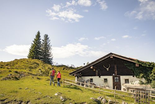 Wanderer vor der Almhütte Koasa Trail Etappe 3 - Region St. Johann in Tirol